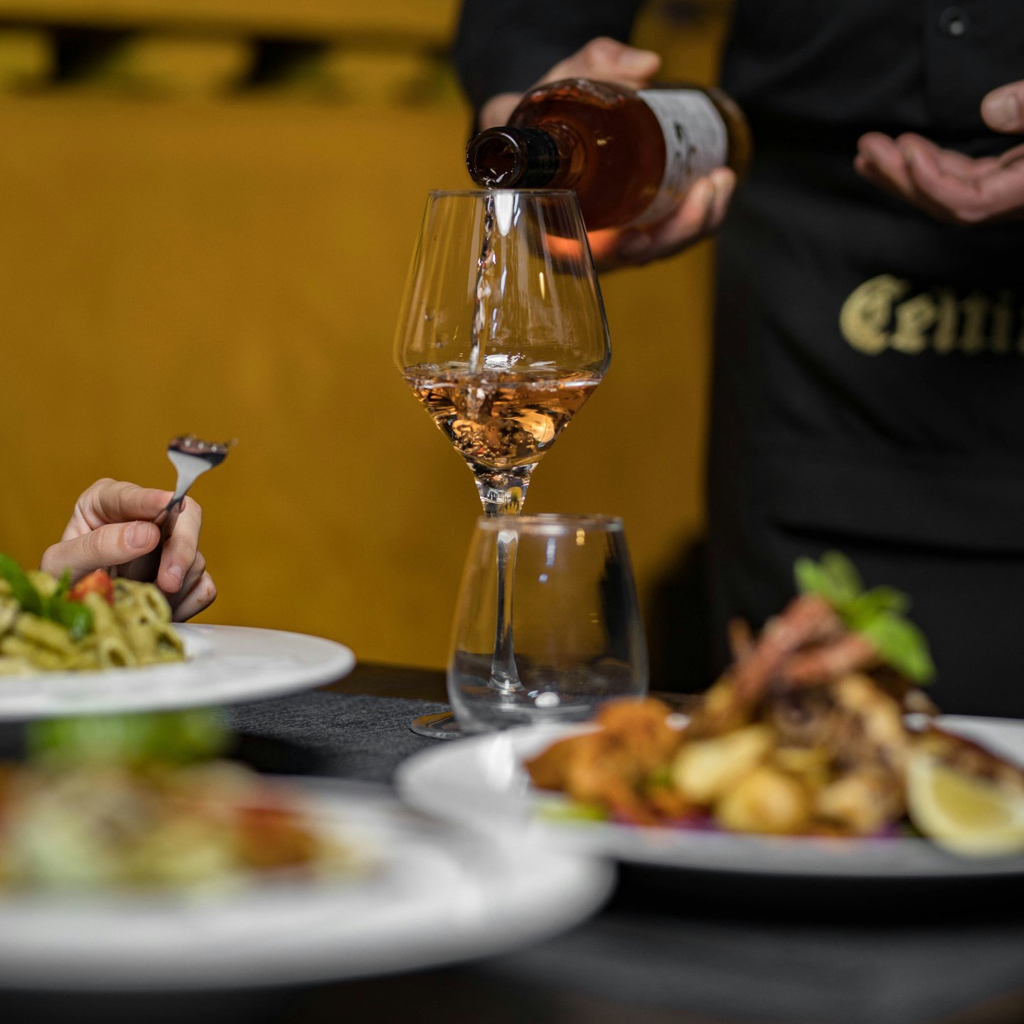 Medewerker schenkt wijn in een glas aan tafel